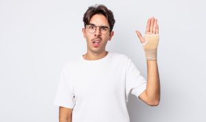 young,hispanic,man,feeling,puzzled,and,confused.,hand,bandage,concept